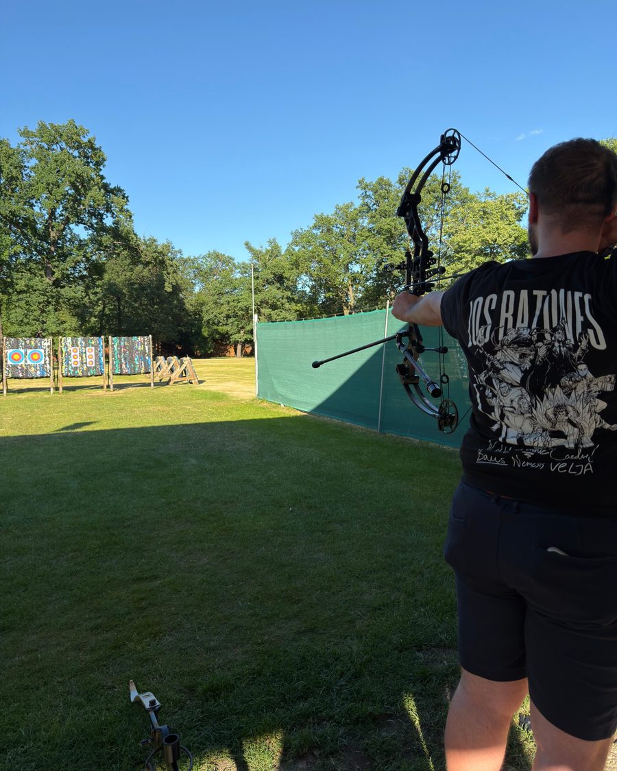 Drawing a compound bow towards targets on an outdoor archery range